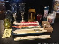 Full view of all items included in the lot: candlesticks with hurricane shades, assorted candles including twisted tapers, pillars, and jar candles.