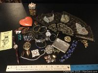 Photo showing entire costume jewelry lot including watches, bracelets, brooches, earrings, and decorative fan with trinket boxes at side.