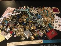 Wide view of a large assortment of costume jewelry on a table including necklaces, brooches, earrings, and pins.
