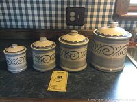 Front view of four ceramic canisters with lids, showing graduated sizes and blue swirl pattern.