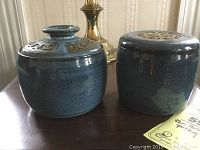 Two blue glazed pottery vessels side by side showing the shapes and brass inlaid lids.