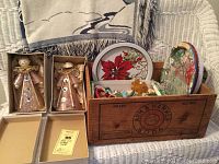 Full view of the vintage wooden Arm and Hammer Soda crate containing multiple Christmas-themed trays, various decorations, and a cozy beige throw draped behind the crate.