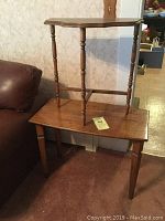 Two wooden tables stacked, showing turned legs and wood surfaces.