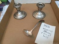 Pair of Empire style weighted sterling silver candlesticks and monogrammed sterling sauce ladle in a cardboard box.