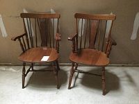Full view of both vintage brace back Windsor chairs showing solid wood construction and classic design.