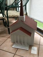 Front and side view of the wooden church model showing white painted walls, red sloped roof, and steeple with removable roof.