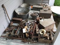 Wide angle view showing large wash tubs, metal boxes, and tools piled densely on porch floor.