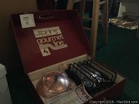 Box open showing copper fondue pot, metal rack burner, and fondue forks in original packaging.