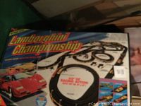 Box front showing Lamborghini Championship logo with a red Lamborghini car and track layout, includes race track pieces illustration and 60' of racing track set up size indication.