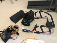 Full view of assorted exercise equipment showing ab machine, rebound shoes, slide board, and bands.
