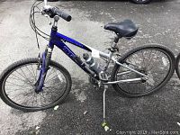 Left side angle of the full bicycle showing blue and gray frame, tires, seat, handlebars, and water bottle.