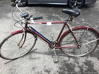 Side view of the full maroon Schwinn World Tourist bicycle showing frame, tires, saddle, and pedals.