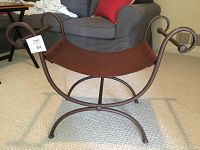 Front view of brown leather seat with metal frame and curled ends of the frame.