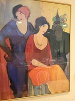 Two women in colorful dresses seated with vase and abstract background