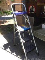 Full view of Werner 3-step aluminum ladder with black slip-resistant steps and red handle tray