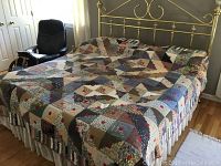 Full view of the king-size quilt spread on a bed, showcasing its multicolored geometric log-cabin style pattern.
