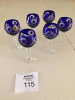 Full view of six cobalt blue stemware glasses arranged together showing shape and cut patterns.