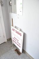 Mirror mounted on wall above sandwich board sign seen partially on floor in corner.