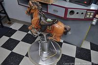 Side view of molded plastic pony and metal base on checkered floor