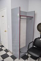 Front and angled view showing the laminate coat closet unit in gray with purple edge trim, metal hanging rod inside, some wear marks and chip on the side panel.