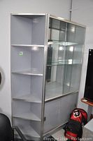 Corner unit with five open shelves shown beside glass display cabinet with mirrored back and sliding glass doors.