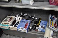 Four Oster clippers in boxes, two hair dryers, match box and crimping tool kit on metal bench