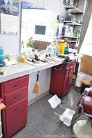 Wide view of barber station with two red pedestals and melamine countertop showing barber tools and items placed on top.