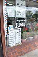 Window display showing 'Sorry, we're CLOSED' sign, business hours, and store information signs including price and service listings.
