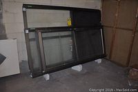 Overall view of the metal framed exterior shop door with glass panels leaning against wall in storage area.