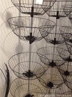 Photo showing side view of multiple metal wire baskets stacked on vertical poles, highlighting the basket structure and spacing.