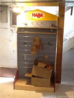 Full view of HABA branded slatwall display unit with cardboard boxes inside the base area