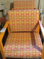 Front view of one chair showing orange-yellow painted wooden frame and multi-color geometric patterned fabric upholstery.