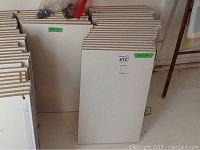 Stack of 27 white shelving boards leaning against a wall, showing clean surfaces and edges.