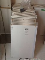 Stack of 29 white laminated particle board shelving boards standing vertically showing front surfaces and dimensions label.