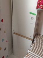 Close up of a single white melamine shelving board with a smooth surface and small hole detail at the edge.