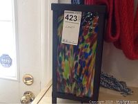 Front view of the lamp displaying colorful stained glass panel and attached auction label