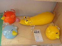 Four hand blown glass pieces arranged on a wooden surface: three birds and one dog, with a handwritten note confirming four pieces of art glass.