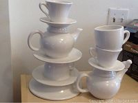 Two stacked tea service styled ceramic flower vases on display on wooden surface