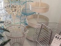 Wide view showing multiple baskets together including white wire baskets, chrome basket, turquoise metal stands, and three-tiered basket stand.
