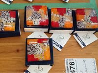 Five Murano glass paperweights in original boxes with colorful floral patterns, placed on wooden surface.
