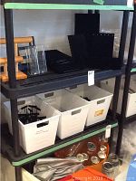 Photo showing black plastic shelving with wood-tone posts, three tiers with various contents removed