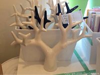 Two ceramic jewelry stands, one white and one black, shown from front angle displaying their tree branch designs and sturdy bases.