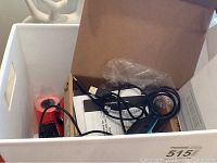 White container with pricing guns, label rolls, and barcode scanner cables inside