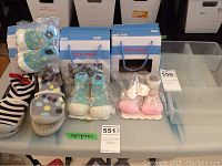 Overview of four pairs of children's footwear including two slip-ons and two pairs of baby booties, displayed on table with tags.