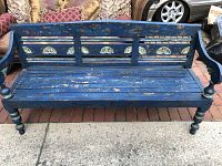 Front view of the blue hand painted wooden bench showing the slatted seat and decorative circular motifs on the backrest.
