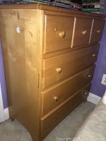Front angled view of a wooden dresser with four drawers and visible surface wear.