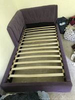 Day bed viewed from above showing lavender upholstery and slatted wooden base, corner design.