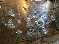 Photo of eleven glasses including nine Italian Grappa glasses with an etched dot design and two crystal champagne coupes