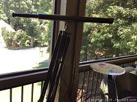 Full side view of a brass and wooden telescope mounted on a wooden tripod outdoors on a porch.