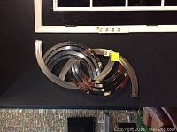 Metal spiral wall art seen laying flat on a black fabric surface with measuring tape for scale.